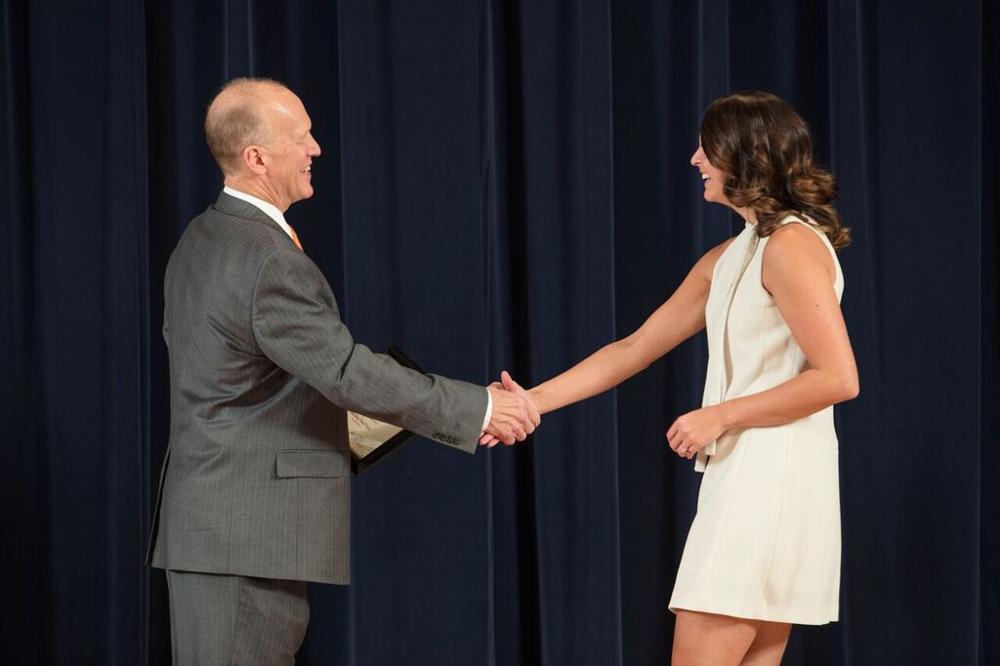 Doctor Potteiger shaking hands with an award recipient in a white dress